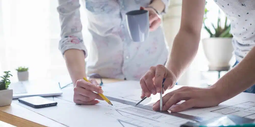 close-up-architecture-hands-working-blueprint-wooden-table-office